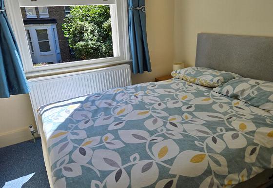 bunk beds in a room with blue mattresses and pillows near a window with curtains showcasing a cozy sleeping space for two people